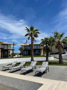 a group of chairs in front of a building with palm trees at Villa fotini in Kallithea Halkidikis