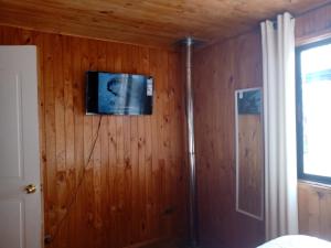 a room with a wooden wall with a television on it at CABAÑA INTERIOR VILLARRICA in Villarrica