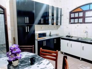 a kitchen with black cabinets and a table with purple flowers at Casa Temporada a 3 quadra da Praia in Praia Grande