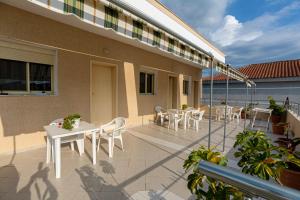 a patio with white tables and chairs on a building at Vila B&E in Vlorë