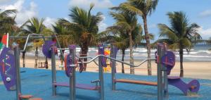 a playground on a beach with palm trees and the ocean at Casa Temporada a 3 quadra da Praia in Praia Grande