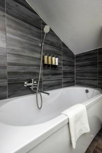 a white bath tub in a bathroom with black tiles at Hotel Marino in Jūrmala
