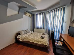 a small bedroom with a bed and a desk at Central Apartment Targovishte in Targovishte