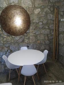 a white table and chairs in front of a stone wall at Casa das Andorinhas in Póvoa de Lanhoso
