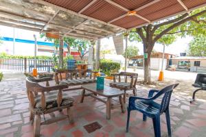 a group of wooden tables and chairs under a pavilion at Ayenda Brisas del Caribe in Santa Marta