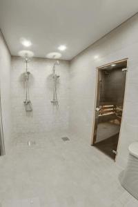 La salle de bains blanche est pourvue d'une douche et de toilettes. dans l'établissement Villa MARIKA plus, à Alajõe