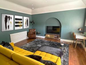 a living room with a yellow couch and a television at 'The Loft' in Yeovil