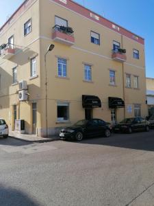 un grande edificio giallo con macchine parcheggiate di fronte di Guia Guest House a São Bartolomeu de Messines