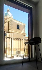 una sedia davanti a una finestra con un edificio di Duomo House a Caltanissetta