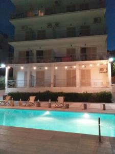 a hotel with a swimming pool in front of a building at Ψιλή Άμμος in Tolo