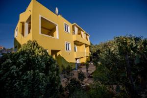 a yellow building with trees in front of it at Apartments Sole in Rab