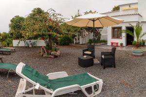 eine Terrasse mit Stühlen, einem Sonnenschirm und einem Tisch in der Unterkunft Bodega Goyo in Puntallana