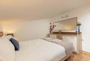 1 dormitorio con cama blanca y espejo grande en Apartment Sea Breeze, en Luštica