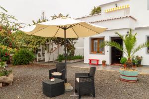 eine Terrasse mit einem Sonnenschirm, Stühlen und einem Tisch in der Unterkunft Bodega Goyo in Puntallana