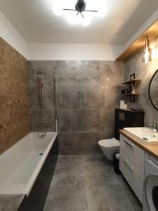 a bathroom with a tub and a toilet and a sink at Noce w Jelonce - Nowoczesny Apartament typu Studio w Centrum Jeleniej G - z garażem dla 1-4 osób in Jelenia Góra +11 photos