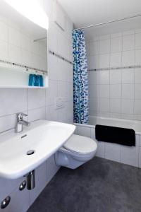 Baño blanco con aseo y lavamanos en Gemütliches Studio in Champfèr/St.Moritz en St. Moritz