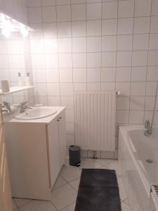 ein Badezimmer mit einem Waschbecken, einer Badewanne und einem Spiegel in der Unterkunft Appartement rez de chaussée avec terrasse et jardin in Tence