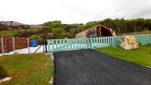 a house with a fence and a gate with a building at Achmelvich View self catering in Lochinver