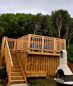 a wooden deck with a wooden stair railing at Achmelvich View self catering in Lochinver