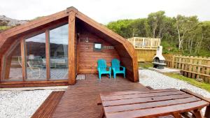 a small cabin with two blue chairs on a deck at Achmelvich View self catering in Lochinver