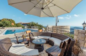 eine Terrasse mit einem Tisch, Stühlen und einem Sonnenschirm in der Unterkunft Villa Marija **** with private pool in Budva