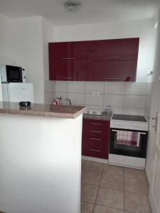 una cucina con armadi rossi e stufa bianca di Apartman Marina a Foča