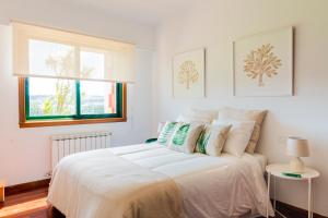 a bedroom with a large white bed with a window at La Casiña in A Coruña +9 photos