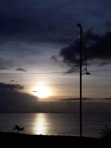 a sunset over the ocean with a street light at AP Comfort Feliz Aurora - Frente Praia do Ariramba in Mosqueiro