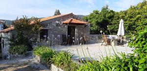 ein Steinhaus mit Sonnenschirm und Terrasse in der Unterkunft Casa do General in Afife
