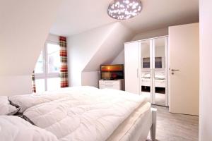 a bedroom with a white bed and a television at Merlin 3 Waldstr 20 h in Kellenhusen