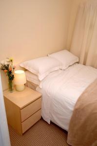 a bedroom with two beds and a table with a vase of flowers at Seaside Cottage in Clacton-on-Sea