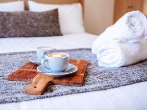 two cups of coffee on a wooden tray on a bed at Astor Inn in Wagga Wagga
