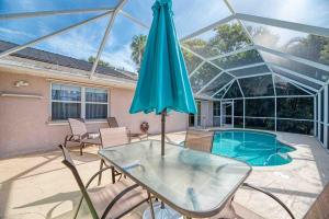 威尼斯的住宿－Vacation Rental by Seminole Dr，一个带玻璃桌和遮阳伞的庭院