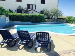 three chairs sitting in front of a swimming pool at Apartment Mirella in Umag