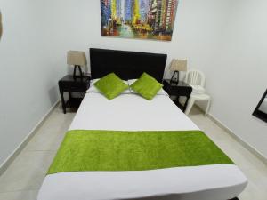 - une chambre avec un grand lit blanc et des oreillers verts dans l'établissement APTO INTERIOR, à Carthagène des Indes
