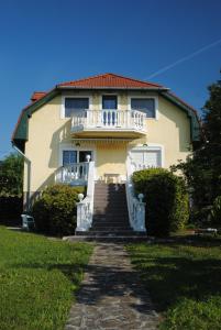 Una gran casa amarilla con un porche blanco y escaleras. en Haus Kristina en Csopak