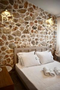 1 dormitorio con 1 cama y pared de piedra en Ktima Panagias en Ormos Panagias