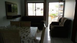 a living room with two chairs and a couch and a television at Apartamento 02 in Garopaba