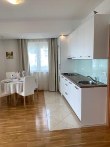 a kitchen with white cabinets and a table with a white table cloth at The Magic Sea View Apartments in Budva +14 photos