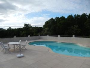 a patio with a table and chairs next to a swimming pool at Chateau Rousselle in Saint-Ciers-de-Canesse