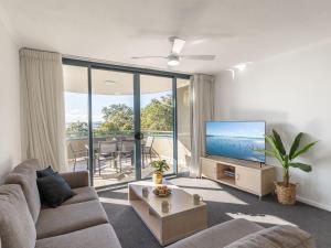 a living room with a couch and a flat screen tv at The Landmark 211 Resort Style holiday with pool games room and restaurant in Nelson Bay