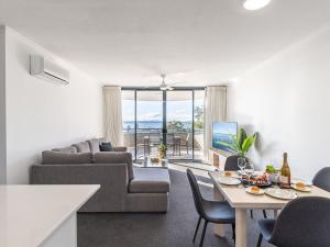 a living room with a couch and a table with chairs at The Landmark 211 Resort Style holiday with pool games room and restaurant in Nelson Bay