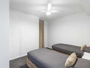 a bedroom with two beds and a ceiling fan at The Landmark 211 Resort Style holiday with pool games room and restaurant in Nelson Bay +15 photos
