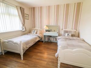 a bedroom with two beds and a mirror at Hazel Cottage in Portrush