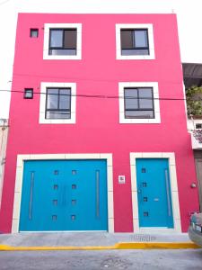 un edificio rosa con puertas azules de garaje delante de él en Casa Republik, en León