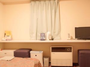a bedroom with a bed and a window with a monitor at Business Hotel Chateau Est Takamatsu in Takamatsu