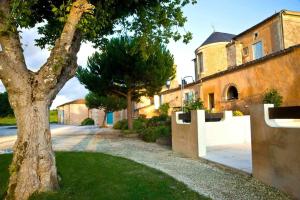 a tree in front of a house with a fence at Chateau Rousselle in Saint-Ciers-de-Canesse