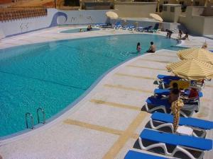 una piscina con sillas, sombrillas y personas en ella en Clube Praia Mar by amcf, en Portimão