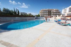 una piscina en un complejo con personas sentadas en sillas en Clube Praia Mar by amcf, en Portimão