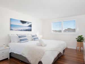 biała sypialnia z łóżkiem i oknem w obiekcie Aloha Beach House w mieście Fingal Bay